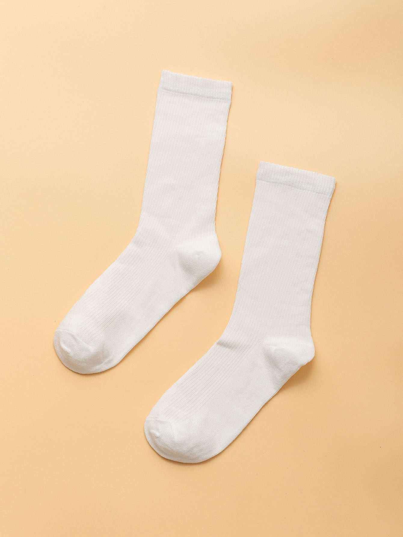 Style reference: two white crew socks arranged on a warm background
