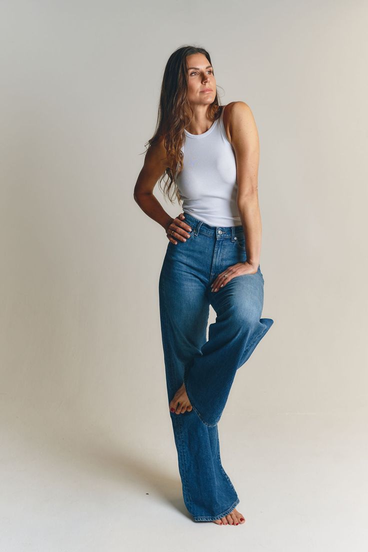 Style reference: a model wearing a white sleeveless tank top with blue jeans